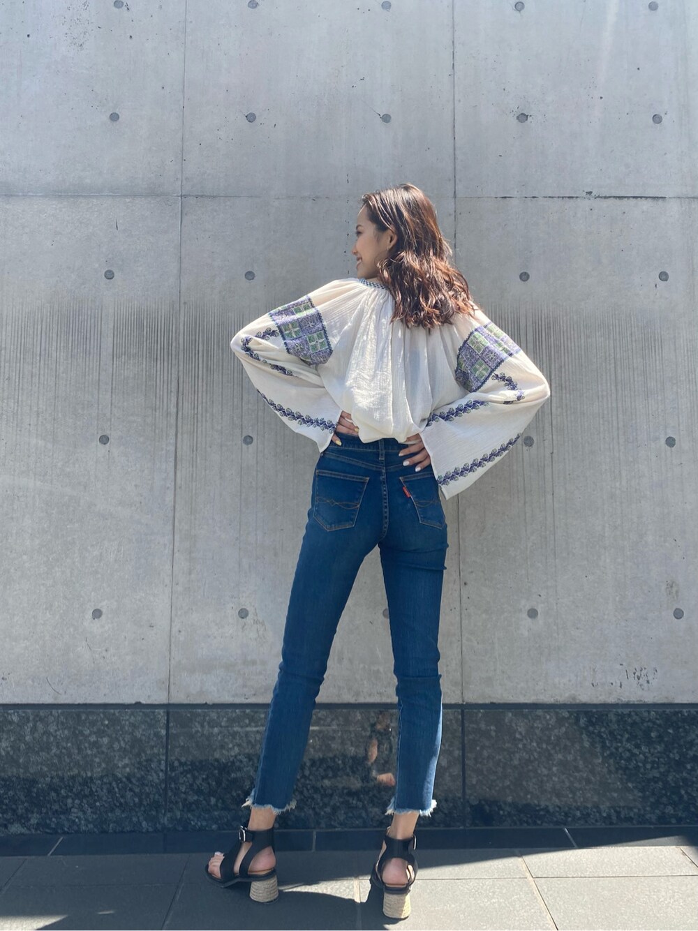 ブルー系のデニムパンツ、ホワイト系のシャツ/ブラウス、ブラック系のサンダルを着用したレディースの春コーディネートの3枚目の写真