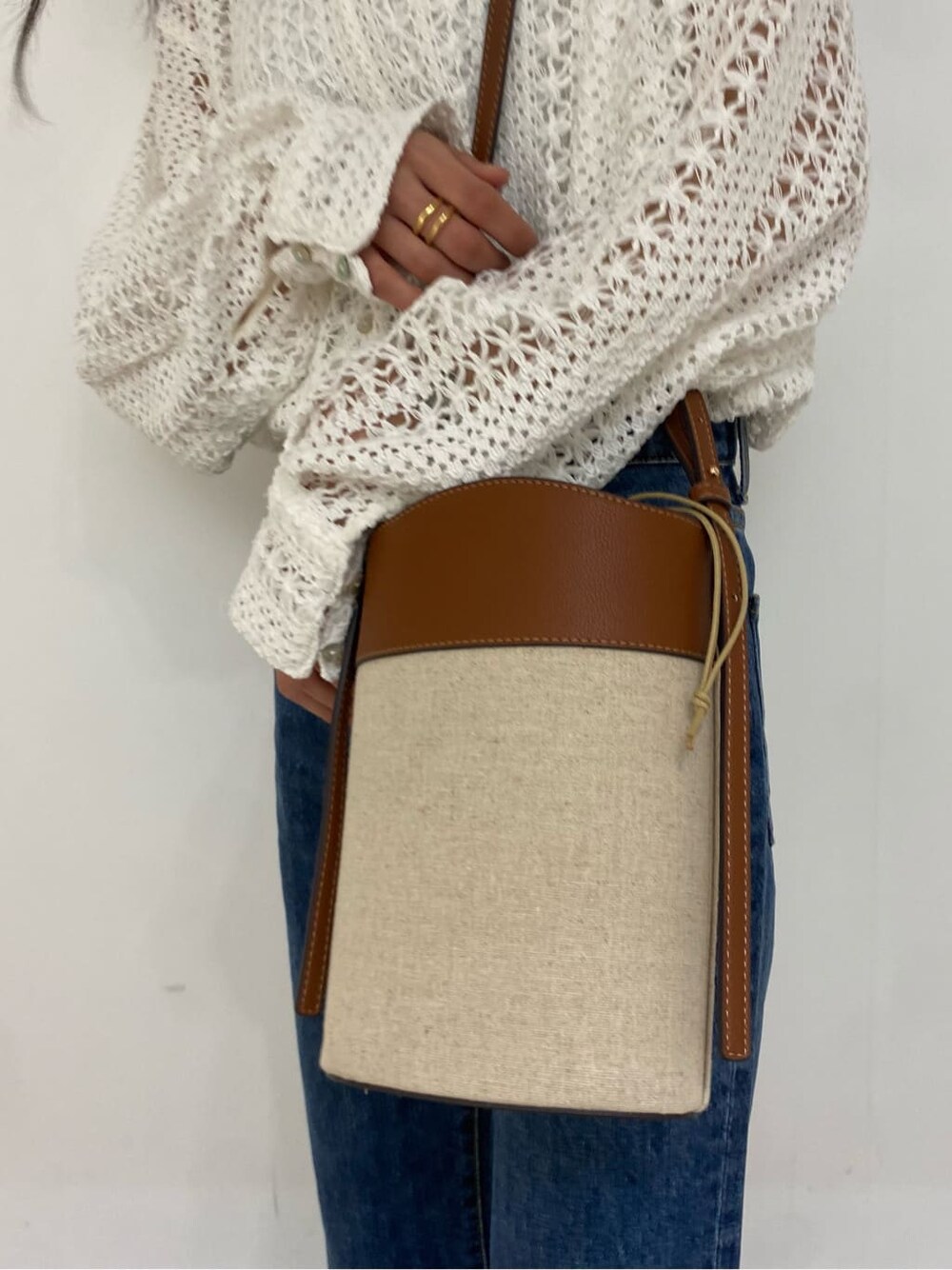 ブラウン系のショルダーバッグ、ブルー系のデニムパンツ、ホワイト系のシャツ/ブラウスを着用したレディースの春コーディネートの6枚目の写真