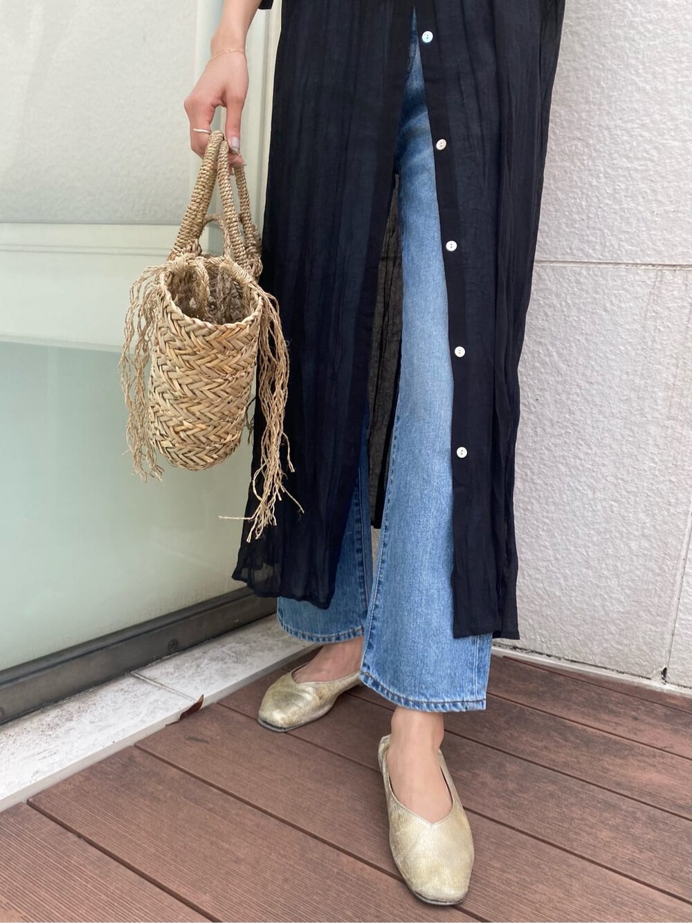 ブルー系のデニムパンツ、ブラック系のワンピース、ベージュ系のかごバッグを着用したレディースの春コーディネートの6枚目の写真
