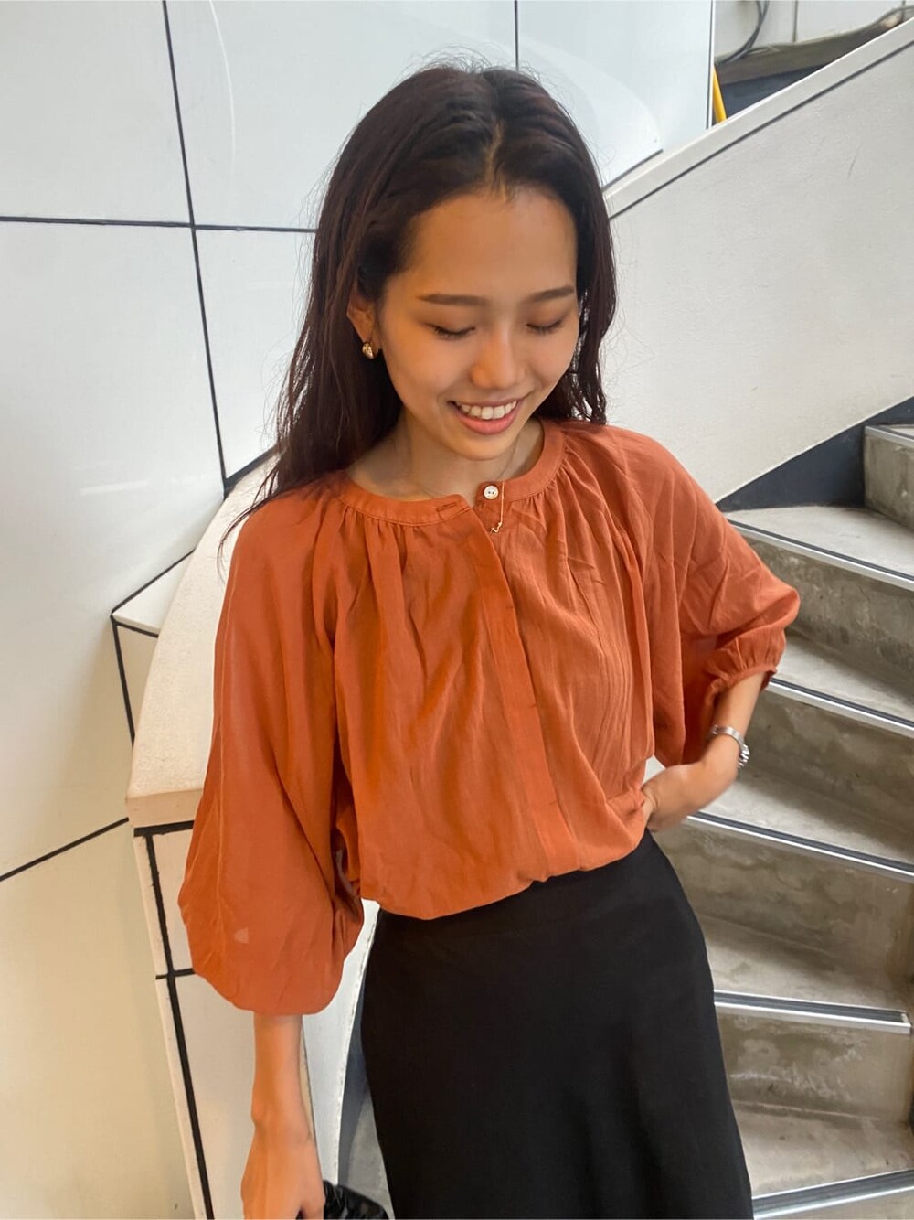 ブラック系のサンダル、オレンジ系のシャツ/ブラウス、ブラック系のスカートを着用したレディースの夏コーディネートの9枚目の写真