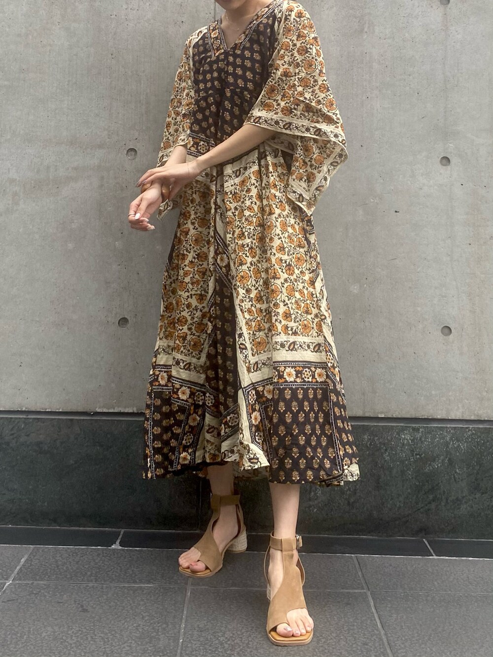 ブラウン系のサンダル、イエロー系のワンピース、ブラウン系のブレスレットを着用したレディースの夏コーディネートの2枚目の写真