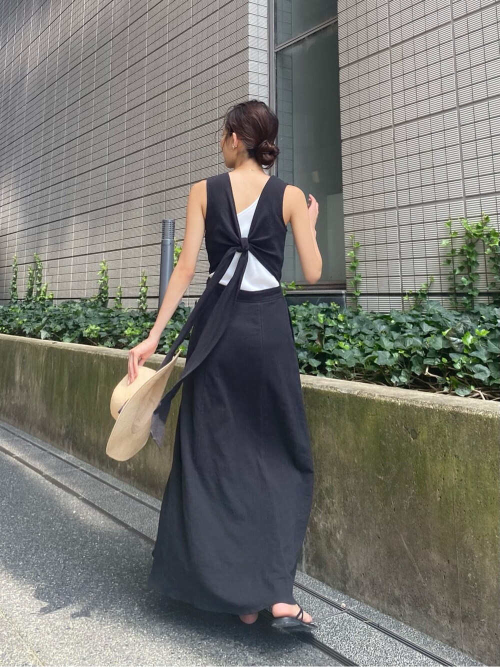 ブラック系のワンピース、ブラック系のサンダル、ホワイト系のタンクトップを着用したレディースの夏コーディネートの2枚目の写真