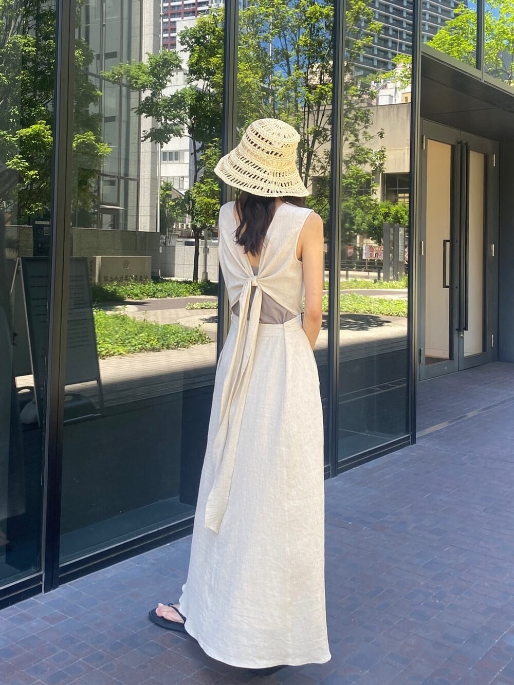 ブラック系のサンダル、ホワイト系のワンピース、ベージュ系のハットを着用したレディースの夏コーディネートの2枚目の写真