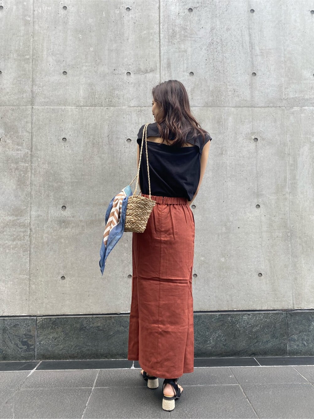 ベージュ系のかごバッグ、ブラック系のタンクトップ、オレンジ系のスカートを着用したレディースの夏コーディネートの3枚目の写真
