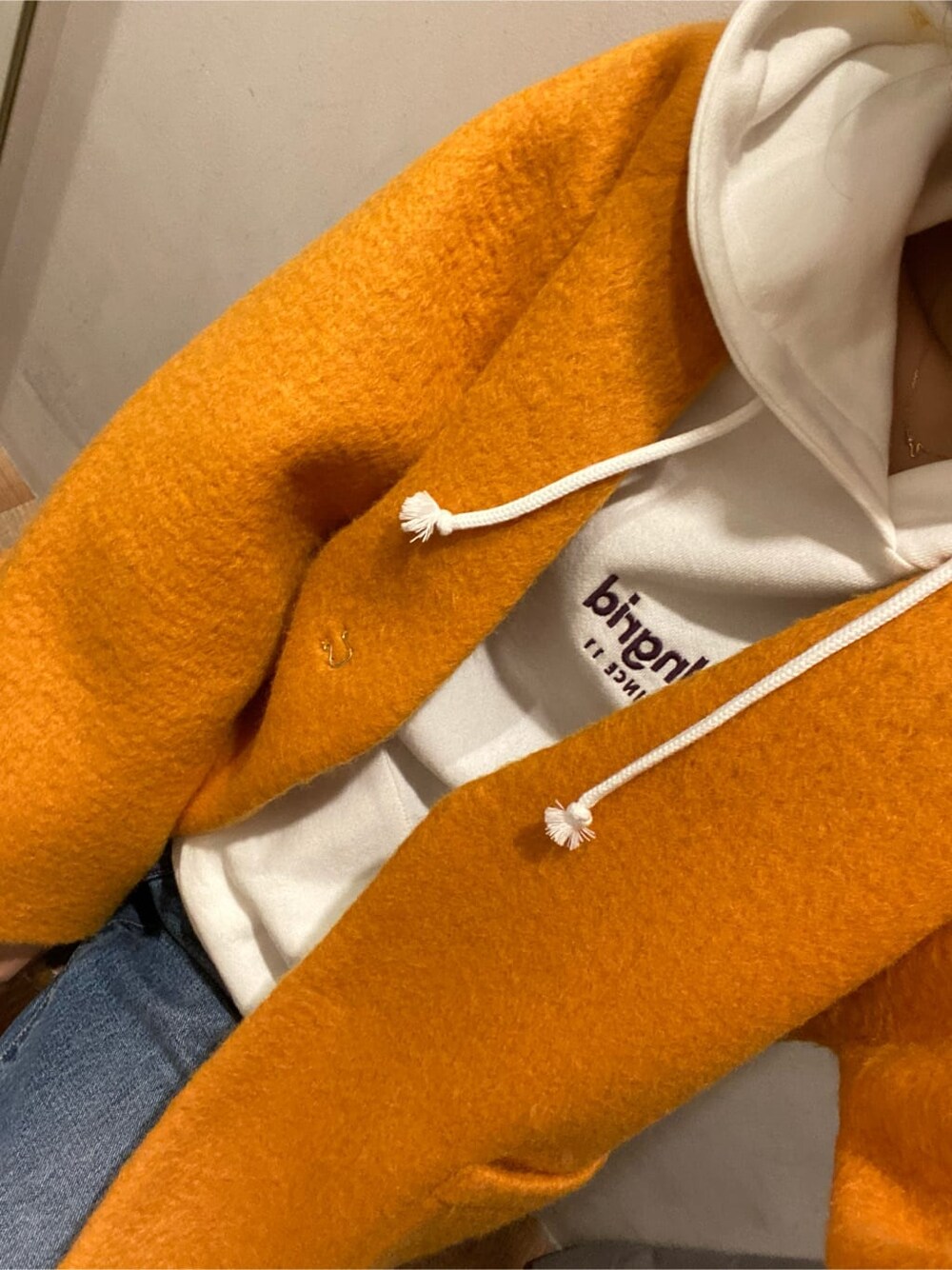 イエロー系のテーラードジャケット、ブラウン系のブーツ、ブルー系のデニムパンツを着用したレディースの秋コーディネートの6枚目の写真