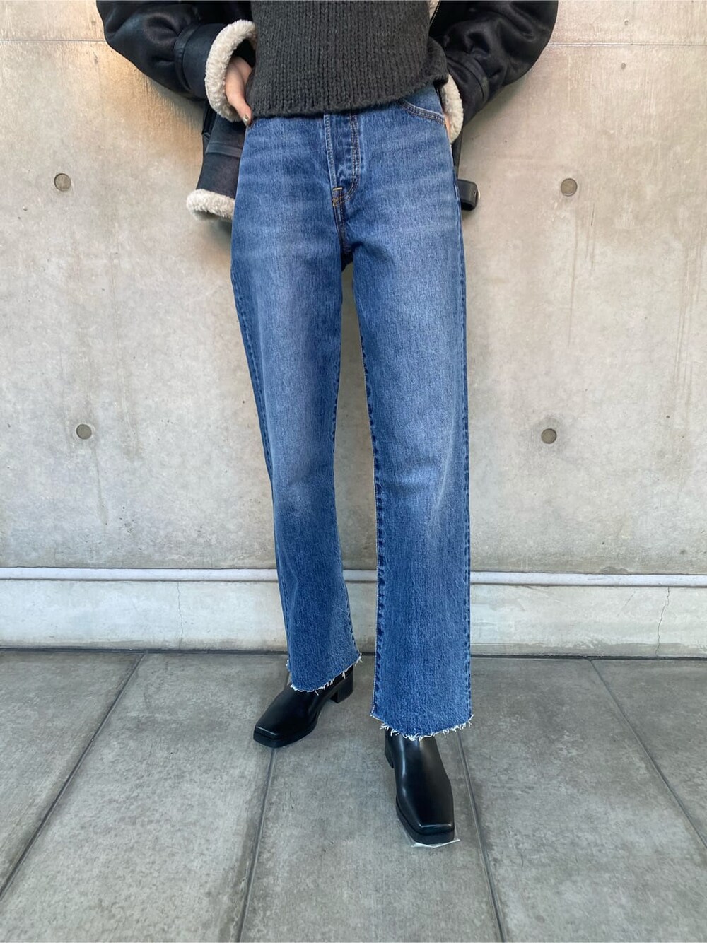 ブラック系のブルゾン、ブルー系のデニムパンツ、グレー系のニット/セーターを着用したレディースの秋コーディネートの6枚目の写真