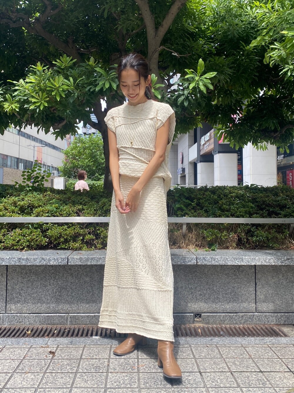 ホワイト系のスカート、ホワイト系のニット/セーター、ゴールド系のネックレスを着用したレディースの夏コーディネートの2枚目の写真