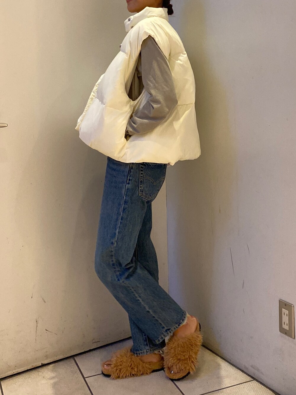 ブルー系のデニムパンツ、グレー系のTシャツ/カットソー、ホワイト系のダウンベストを着用したレディースの秋コーディネートの2枚目の写真