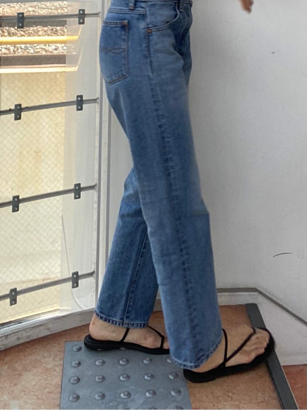 ブルー系のデニムパンツ、ブラック系のハットを着用したレディースの夏コーディネートの3枚目の写真