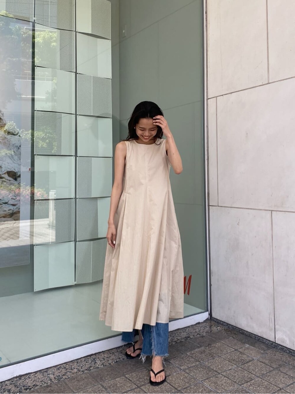 ブルー系のデニムパンツ、ベージュ系のワンピースを着用したレディースの春コーディネートの2枚目の写真