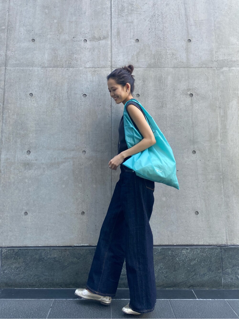ブルー系のハンドバッグ、ブルー系のデニムパンツ、グレー系のタンクトップを着用したレディースの春コーディネートの2枚目の写真