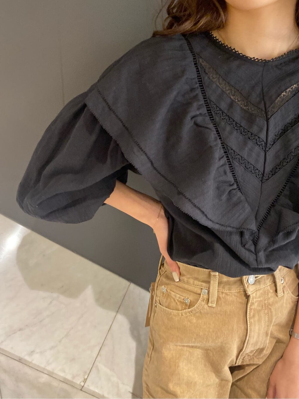 ブラック系のシャツ/ブラウス、ブラック系のハンドバッグ、ベージュ系のデニムパンツを着用したレディースの冬コーディネートの7枚目の写真