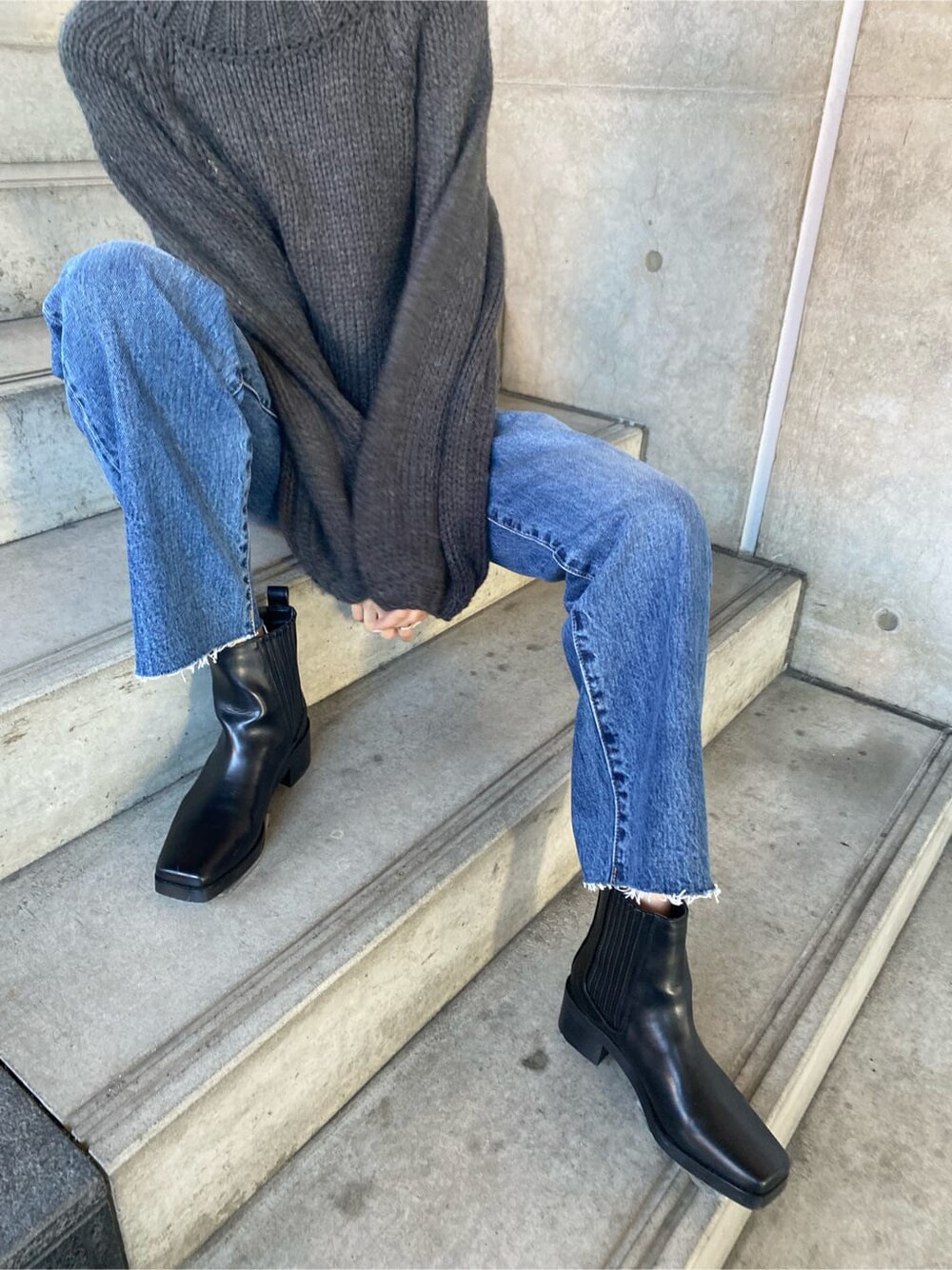 ブラック系のブルゾン、ブルー系のデニムパンツ、グレー系のニット/セーターを着用したレディースの秋コーディネートの9枚目の写真