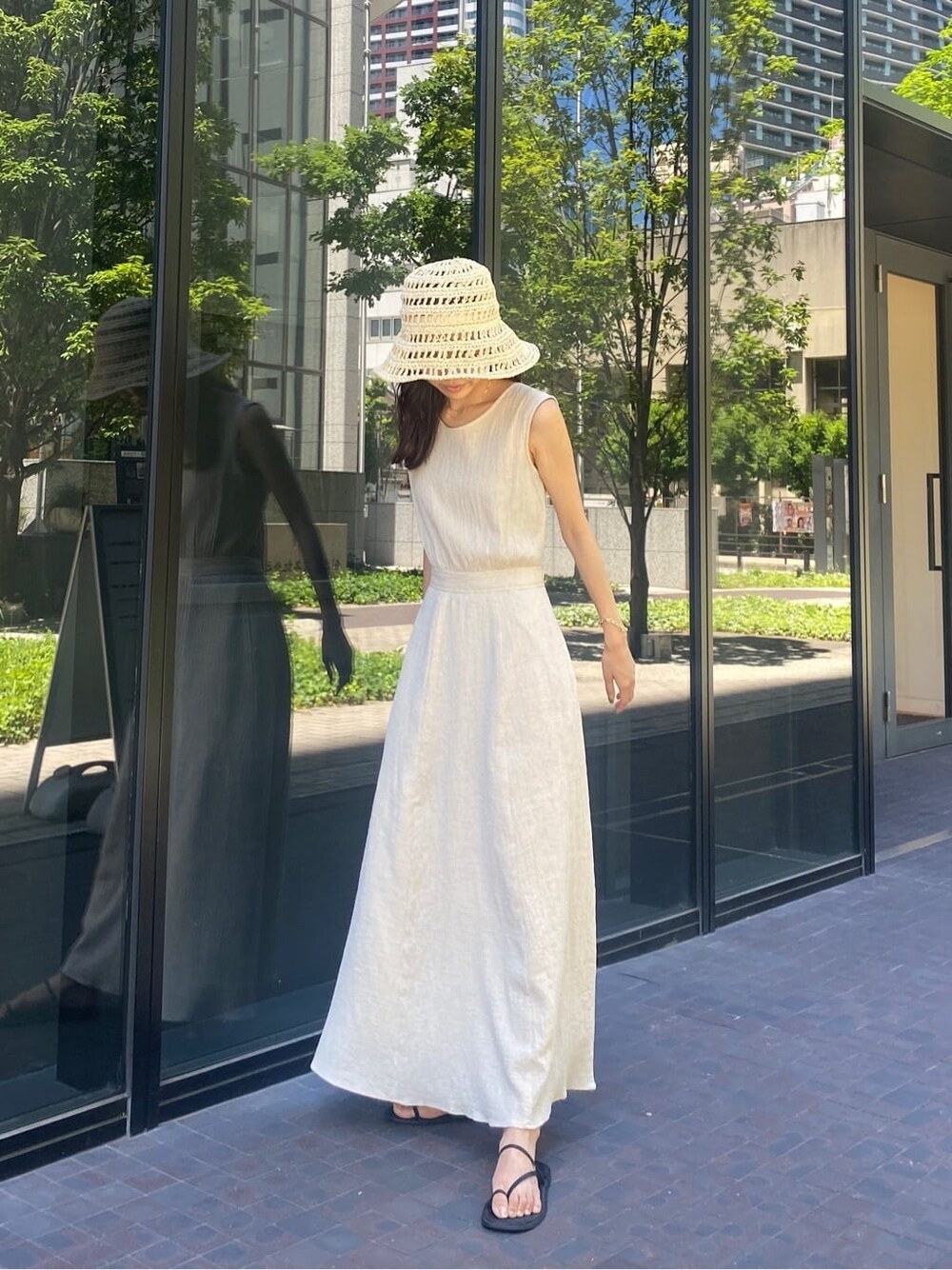 ブラック系のサンダル、ホワイト系のワンピース、ベージュ系のハットを着用したレディースの夏コーディネートの3枚目の写真