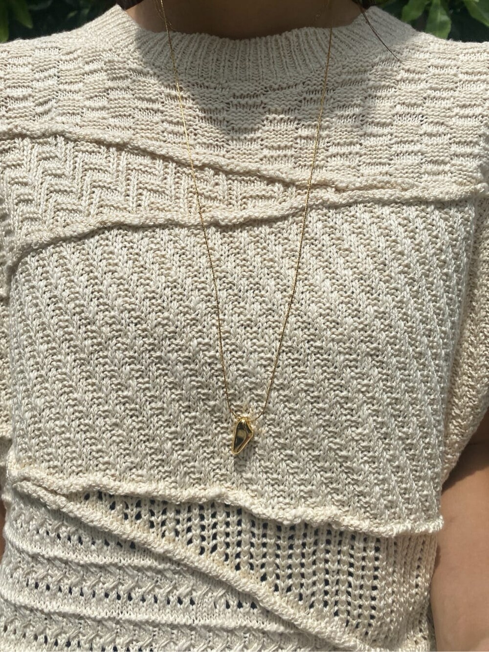 ホワイト系のスカート、ホワイト系のニット/セーター、ゴールド系のネックレスを着用したレディースの夏コーディネートの6枚目の写真