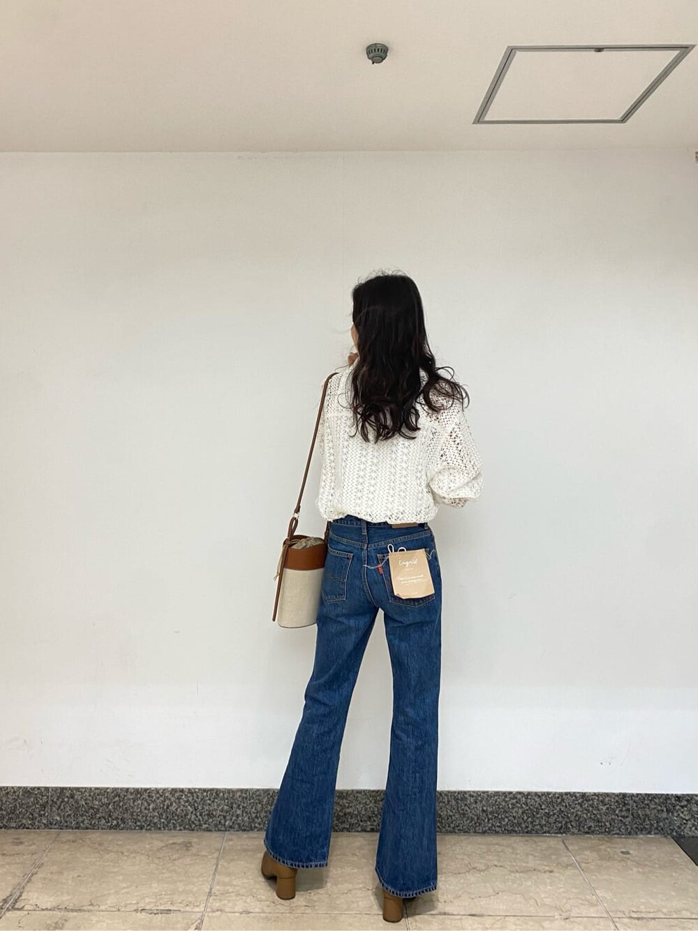 ブラウン系のショルダーバッグ、ブルー系のデニムパンツ、ホワイト系のシャツ/ブラウスを着用したレディースの春コーディネートの3枚目の写真