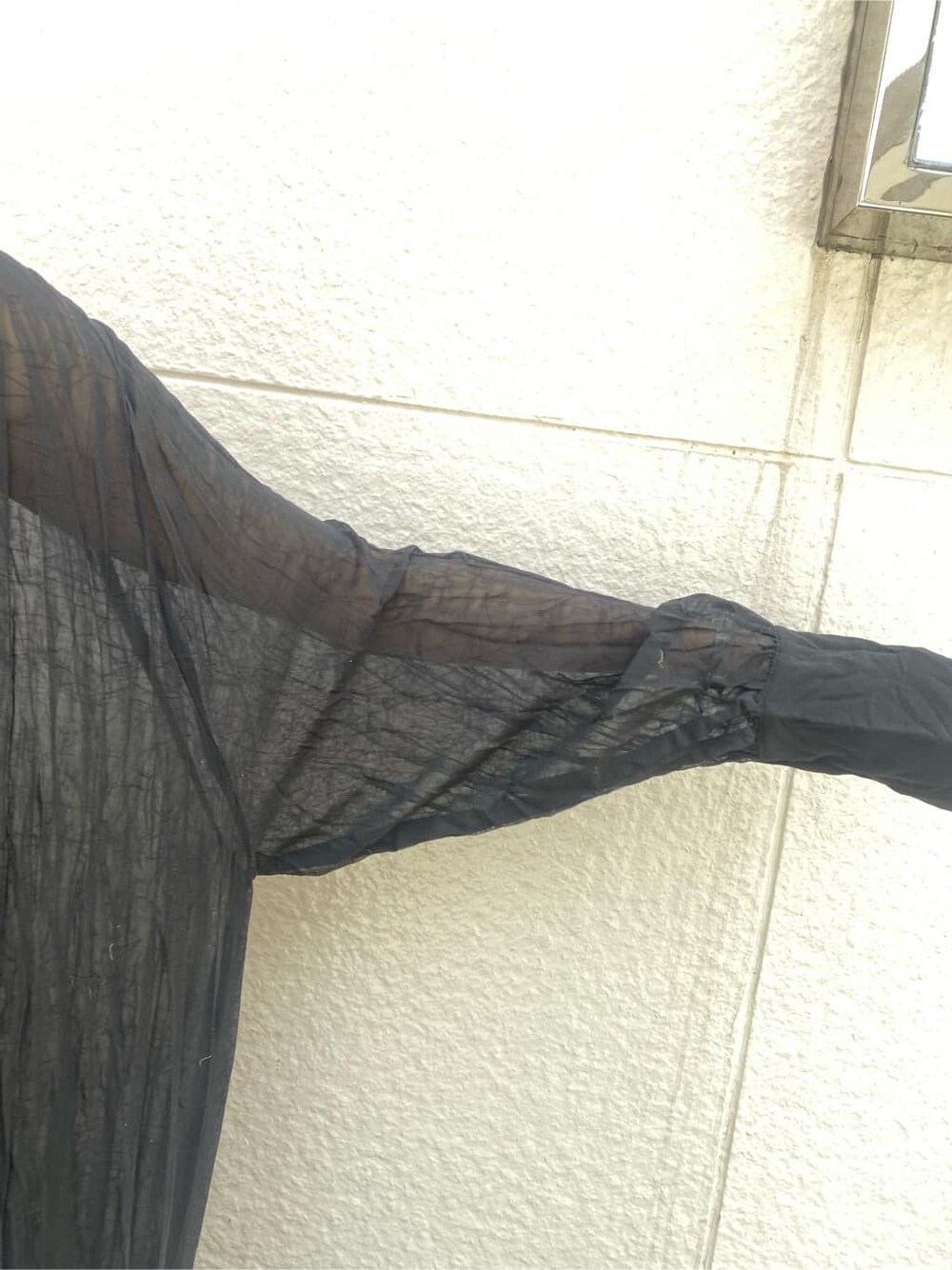 ブルー系のデニムパンツ、ブラック系のワンピース、ベージュ系のかごバッグを着用したレディースの春コーディネートの5枚目の写真
