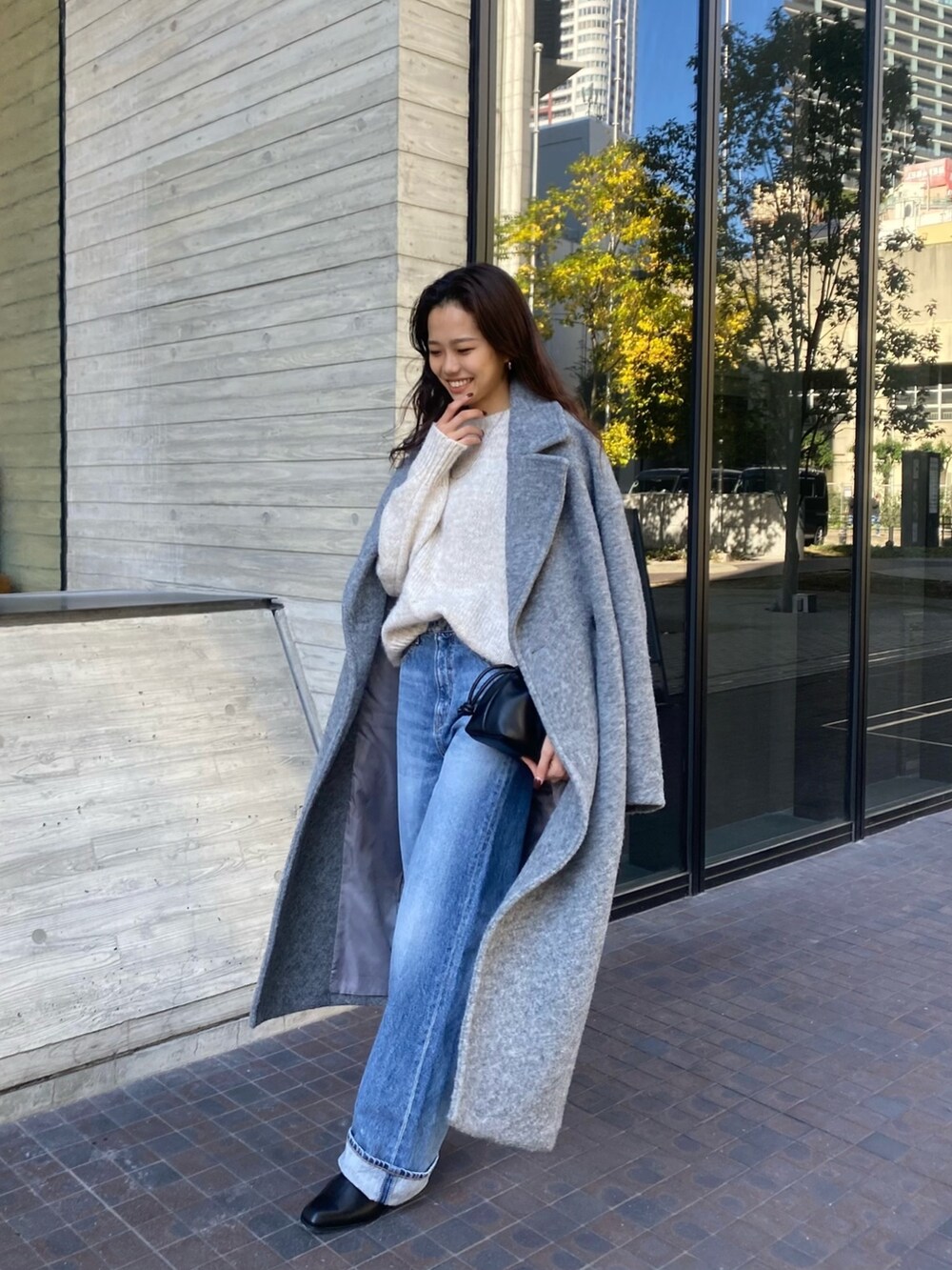 ホワイト系のニット/セーター、グレー系のチェスターコート、ブルー系のデニムパンツを着用したレディースの秋コーディネートの2枚目の写真