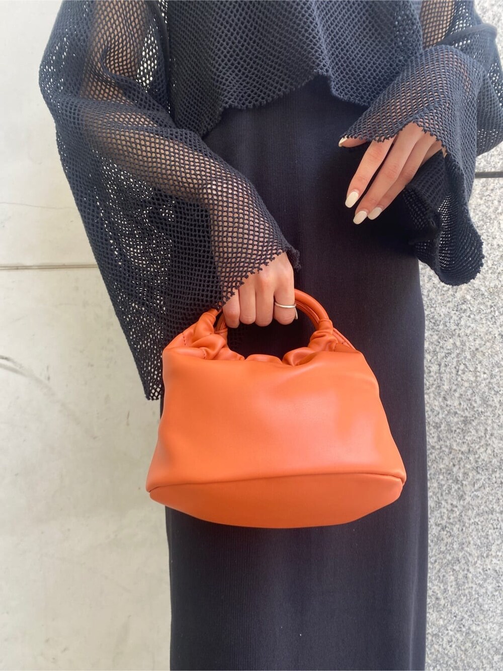 ブラック系のTシャツ/カットソー、ブラック系のワンピース、オレンジ系のハンドバッグを着用したレディースの春コーディネートの8枚目の写真