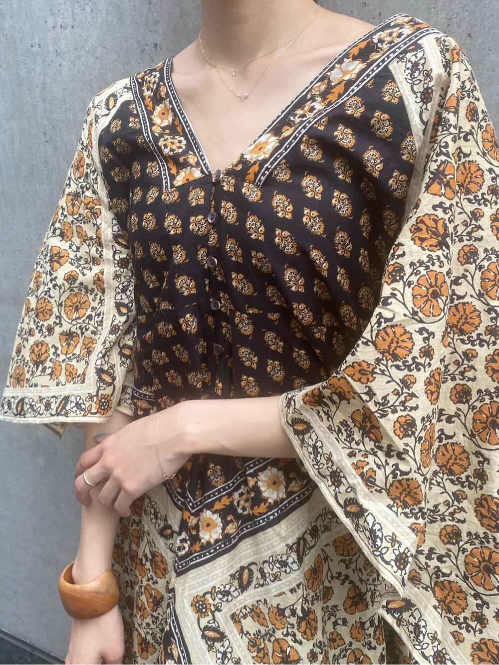 ブラウン系のサンダル、イエロー系のワンピース、ブラウン系のブレスレットを着用したレディースの夏コーディネートの3枚目の写真