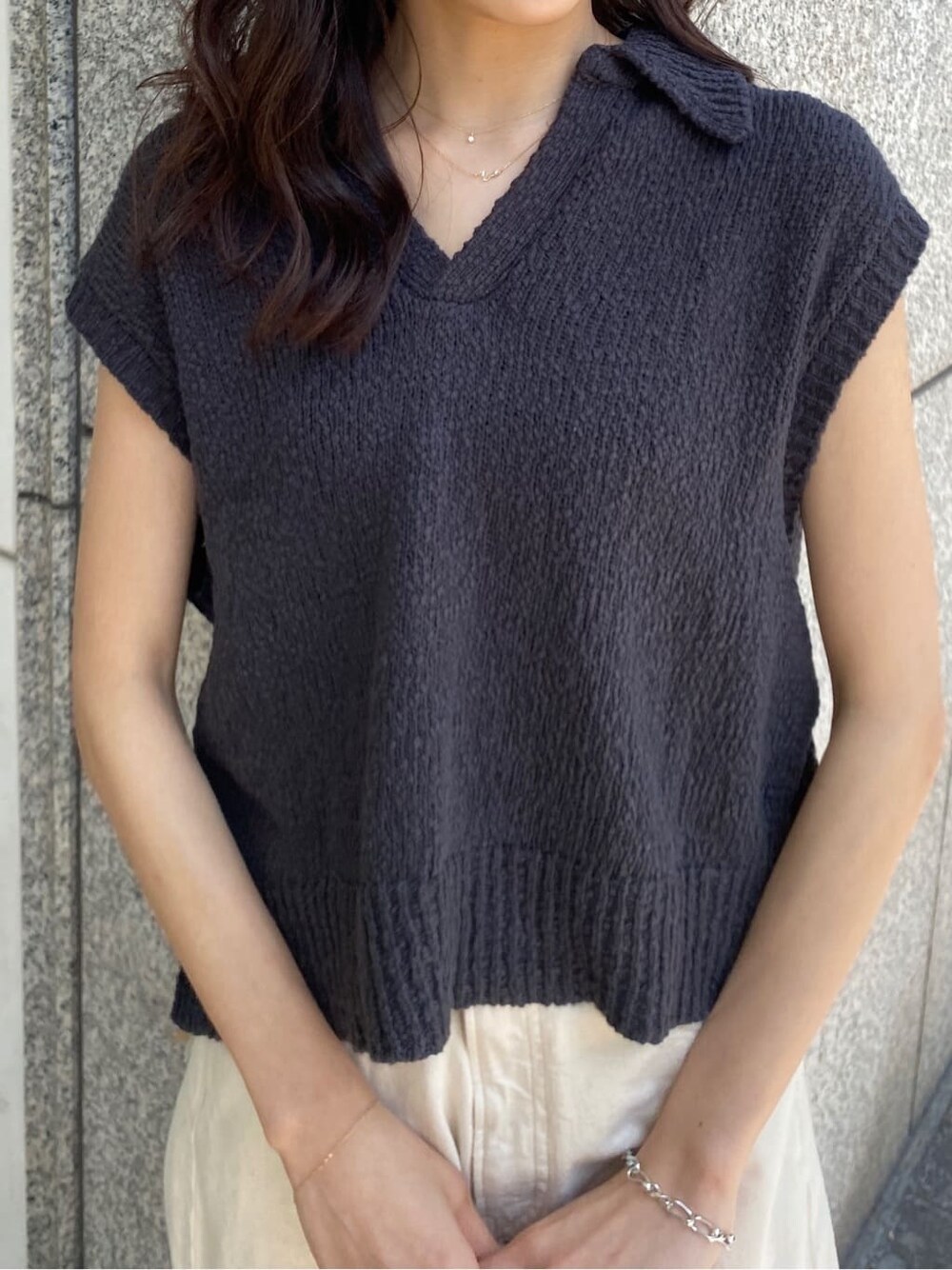 オレンジ系のハンドバッグ、ホワイト系のデニムパンツ、グレー系のベストを着用したレディースの春コーディネートの5枚目の写真