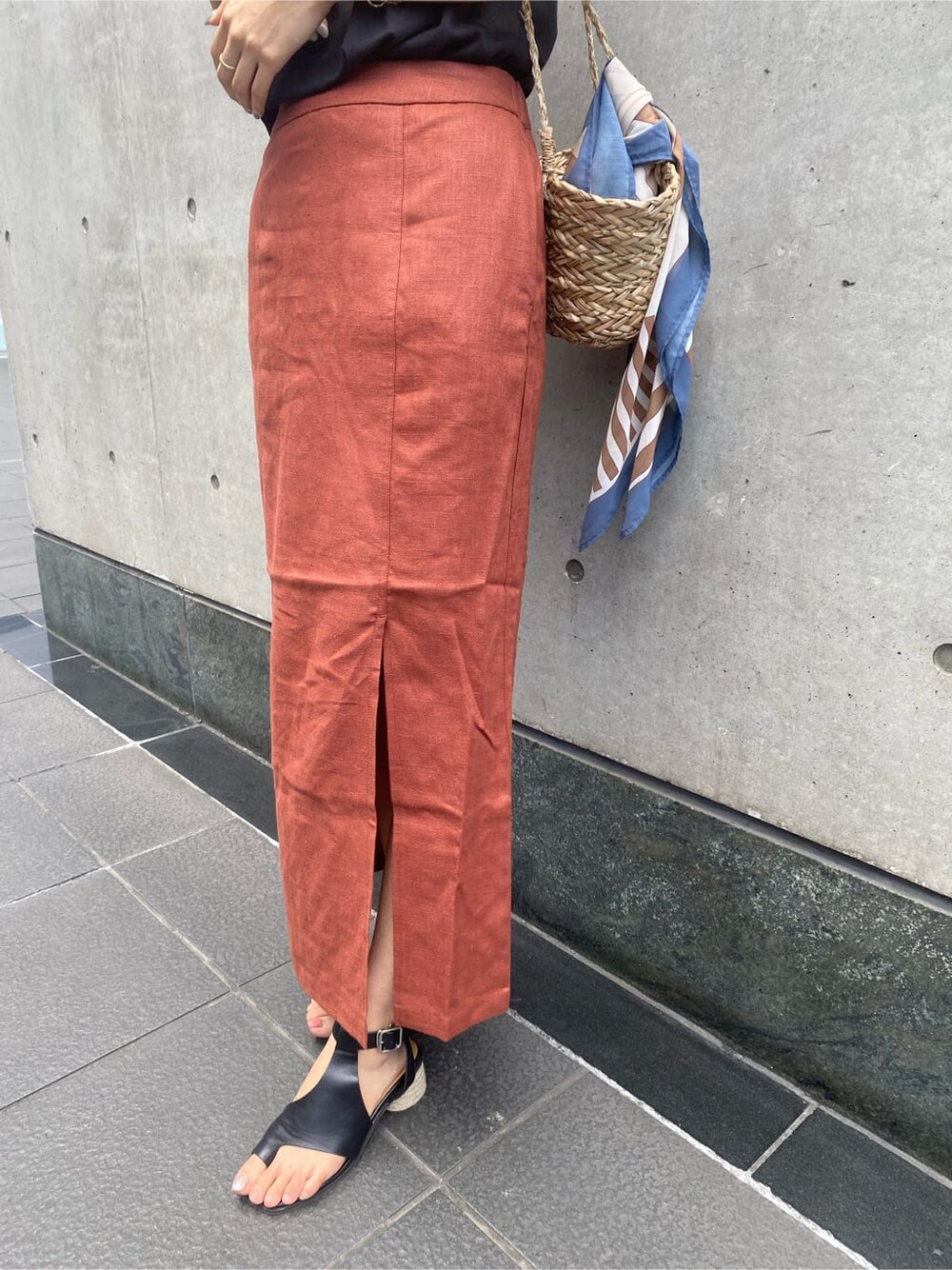 ベージュ系のかごバッグ、ブラック系のタンクトップ、オレンジ系のスカートを着用したレディースの夏コーディネートの5枚目の写真