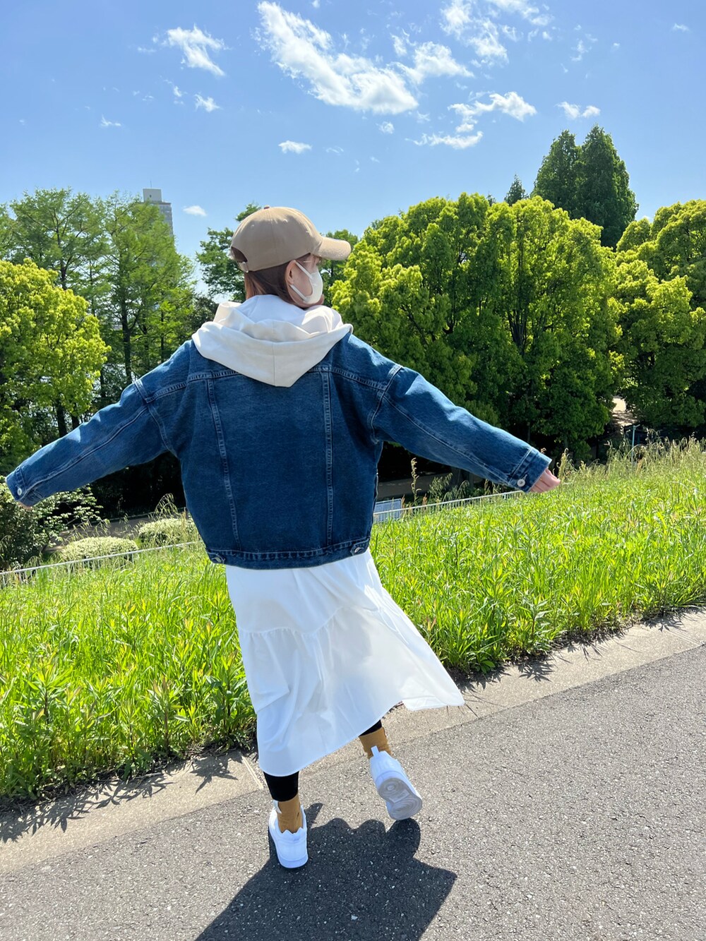 ホワイト系のパーカー、ブルー系のデニムジャケット、ベージュ系のベストを着用したレディースの春コーディネートの3枚目の写真
