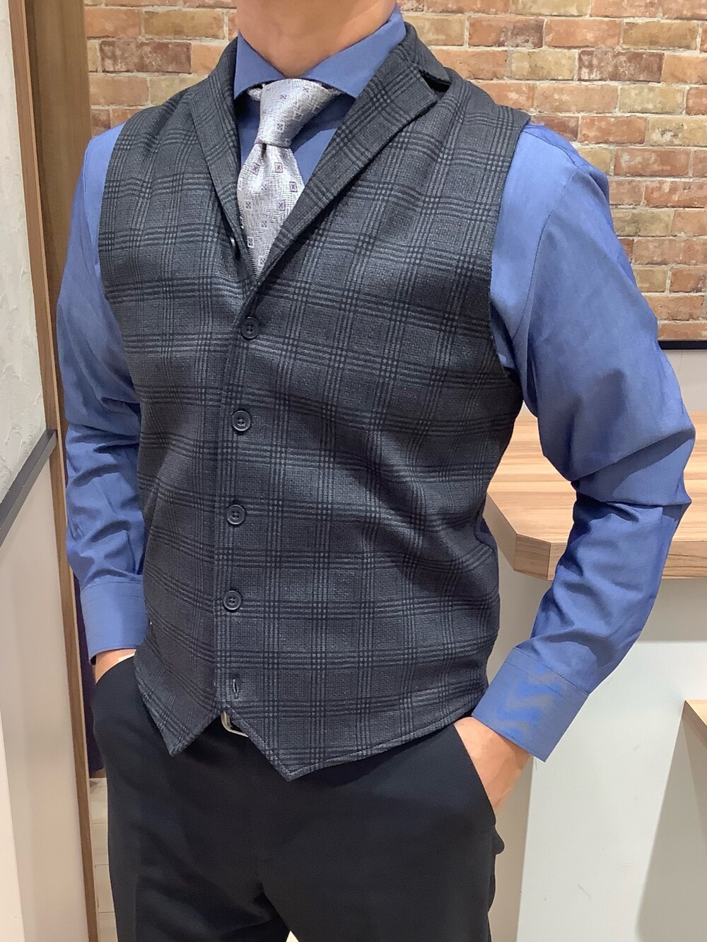 シルバー系のネクタイ、ブルー系のベスト、ブルー系のビジネスシャツを着用したメンズの秋コーディネートの2枚目の写真