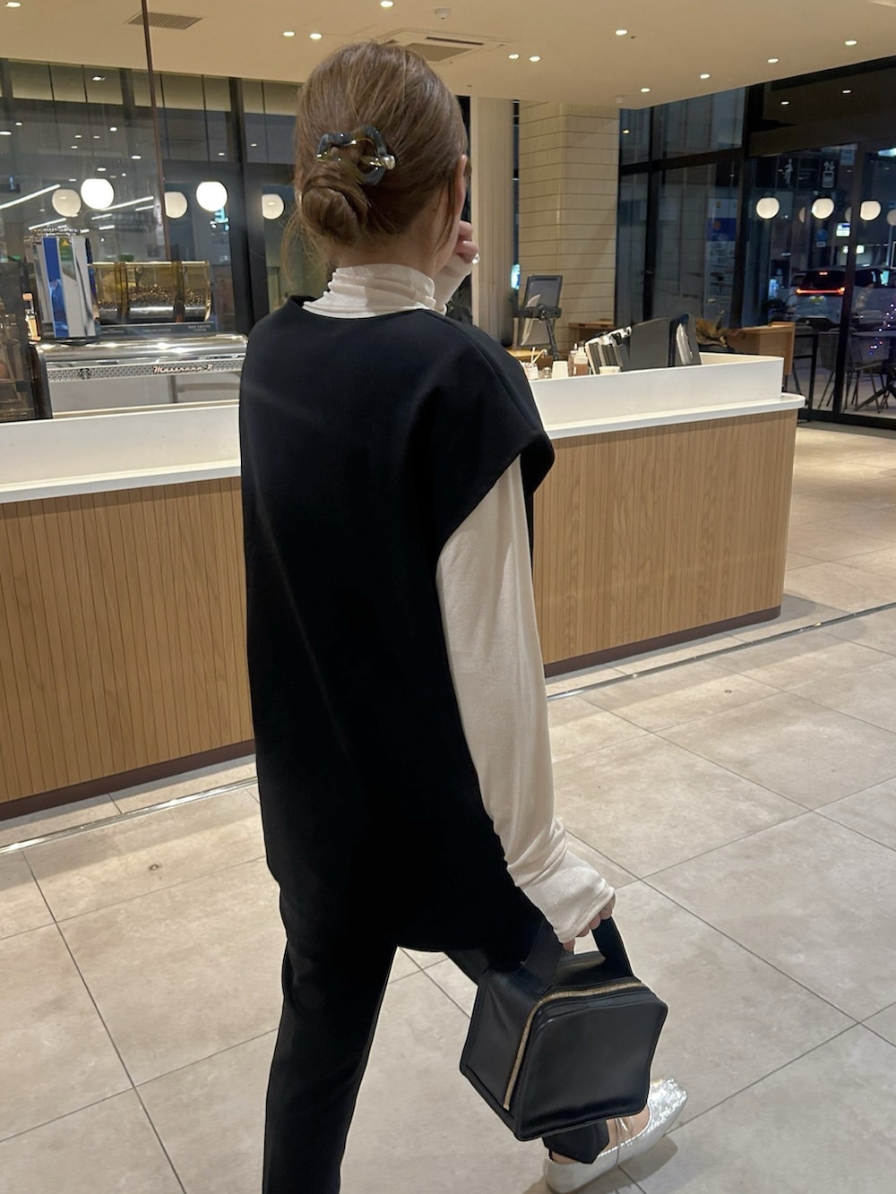 ブラック系のベスト、ブラック系のパンツを着用したレディースの春コーディネートの3枚目の写真