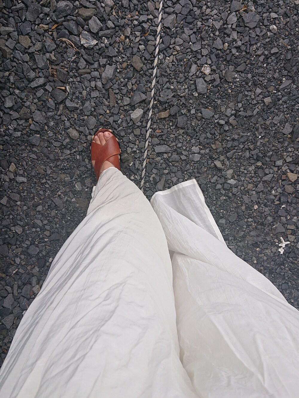 ブラウン系のベスト、ホワイト系のパンツ、ブラウン系のサンダルを着用したレディースの夏コーディネートの3枚目の写真