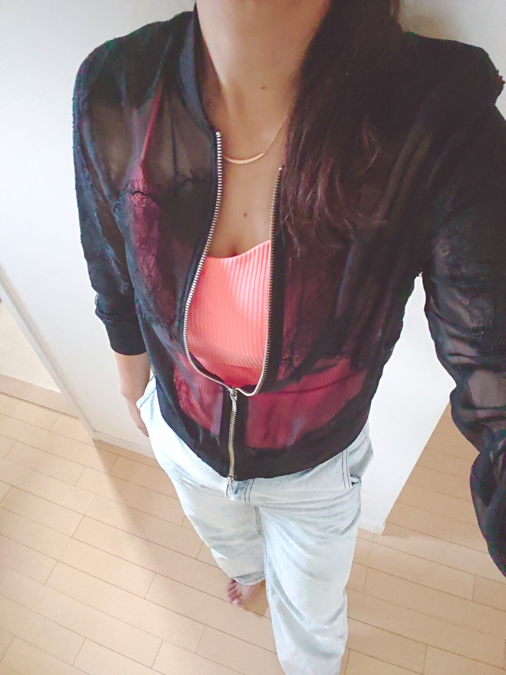 ブルー系のデニムパンツ、オレンジ系のキャミソール、ブラック系のブルゾンを着用したレディースの秋コーディネートの2枚目の写真