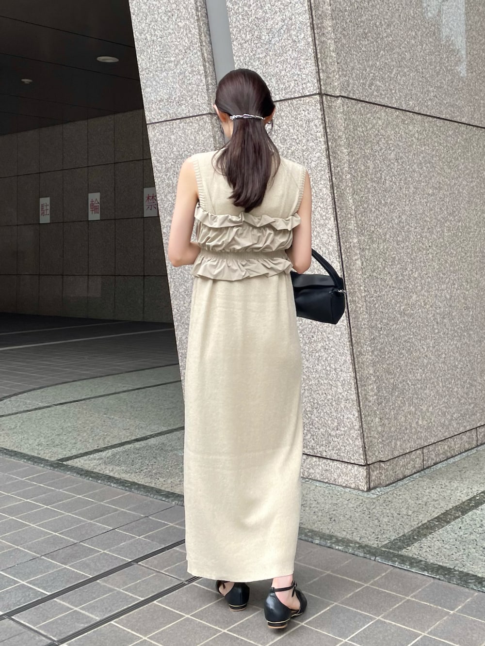 ブラック系のパンプス、ベージュ系のワンピース、ブラック系のショルダーバッグを着用したレディースの夏コーディネートの4枚目の写真