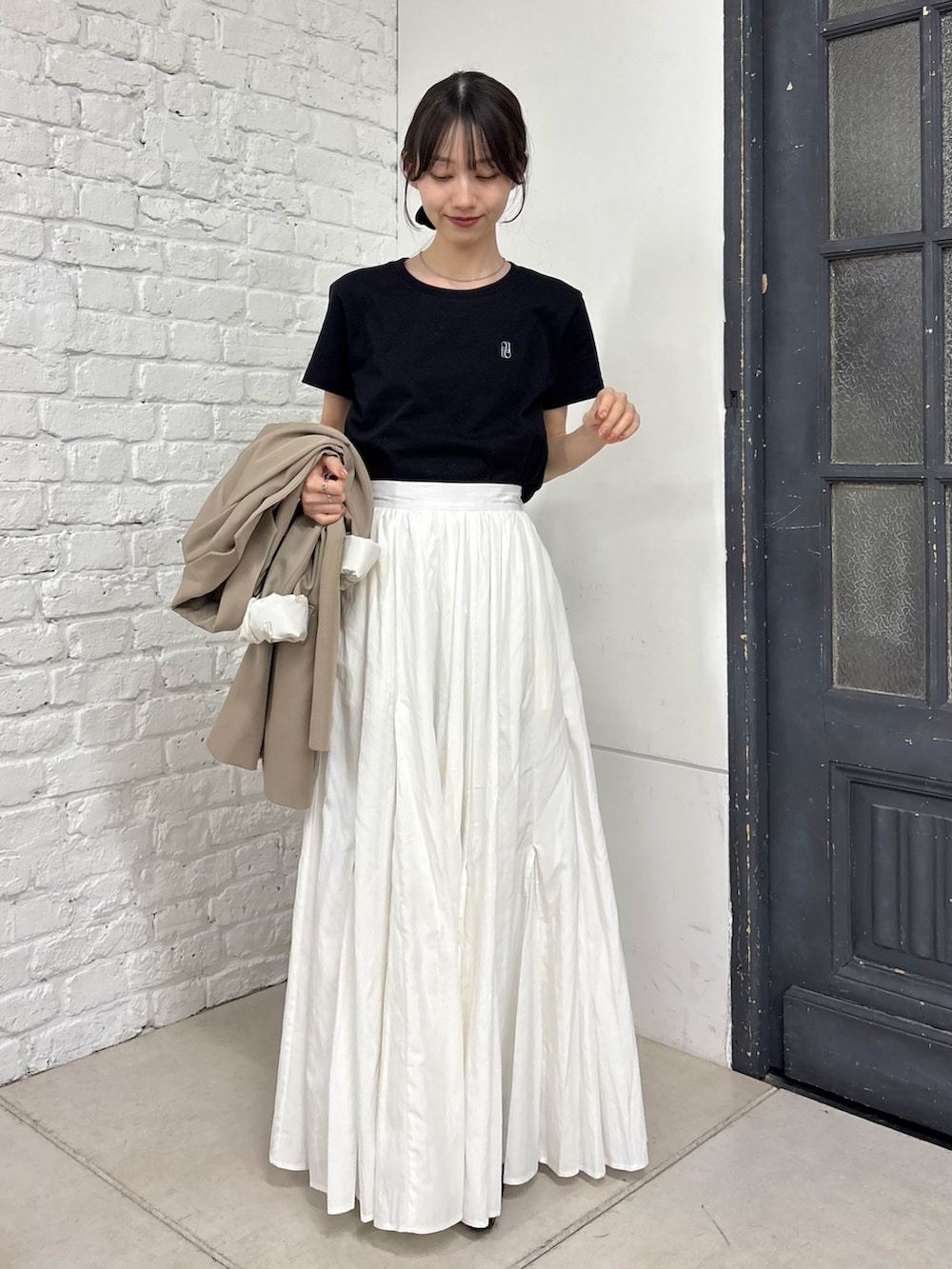 ホワイト系のスカート、ベージュ系のテーラードジャケット、ブラック系のTシャツ/カットソーを着用したレディースの春コーディネートの3枚目の写真