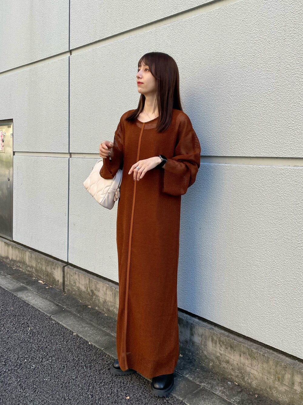 ブラウン系のワンピース、ブラック系のブーツ、ホワイト系のボストンバッグを着用したレディースの秋コーディネートの2枚目の写真