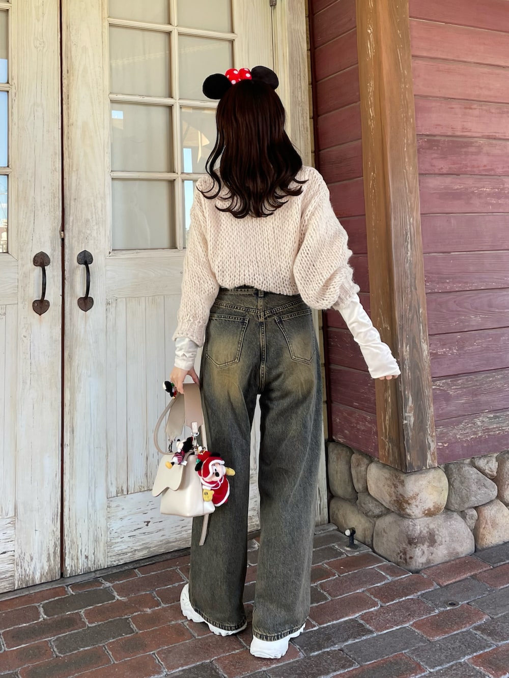 ホワイト系のニット/セーター、ブラウン系のデニムパンツ、ホワイト系のスニーカーを着用したレディースの冬コーディネートの3枚目の写真