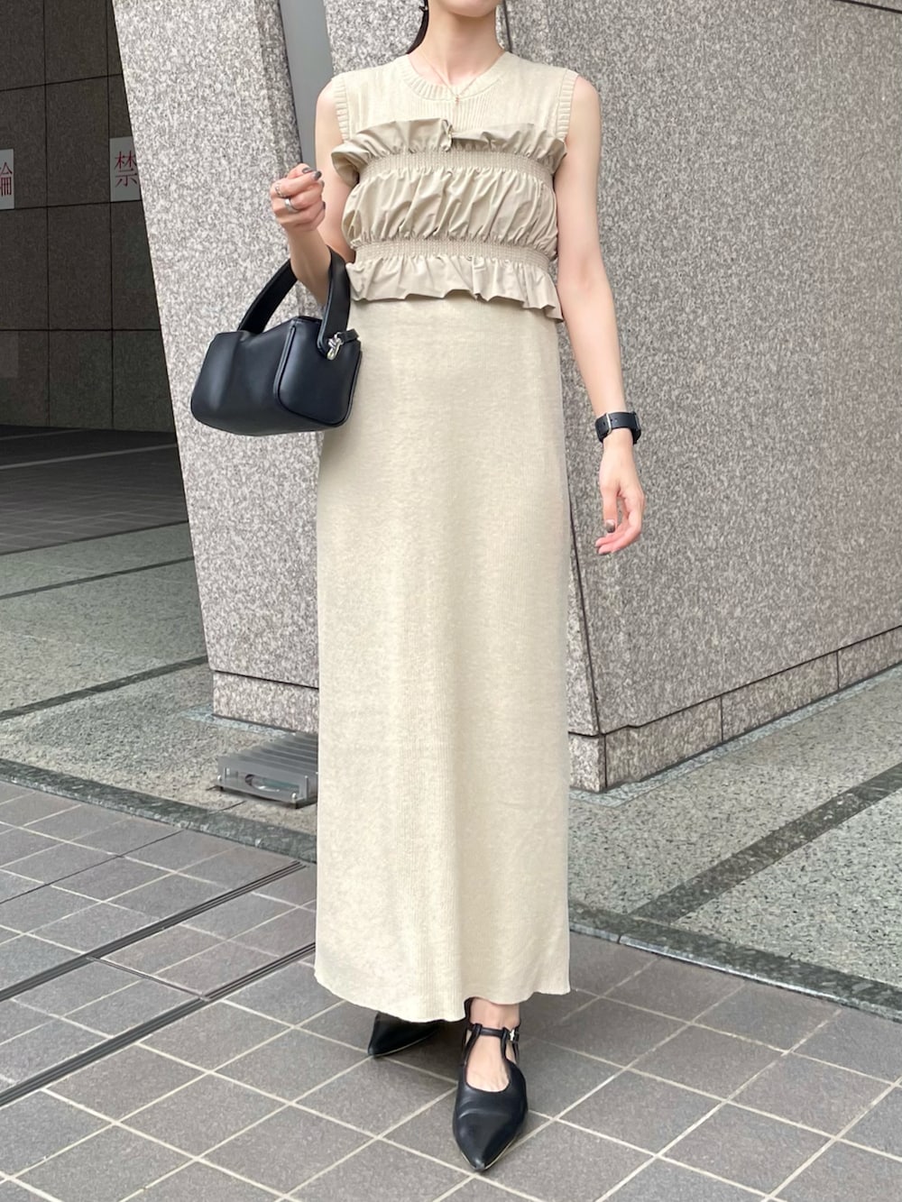 ブラック系のパンプス、ベージュ系のワンピース、ブラック系のショルダーバッグを着用したレディースの夏コーディネートの2枚目の写真