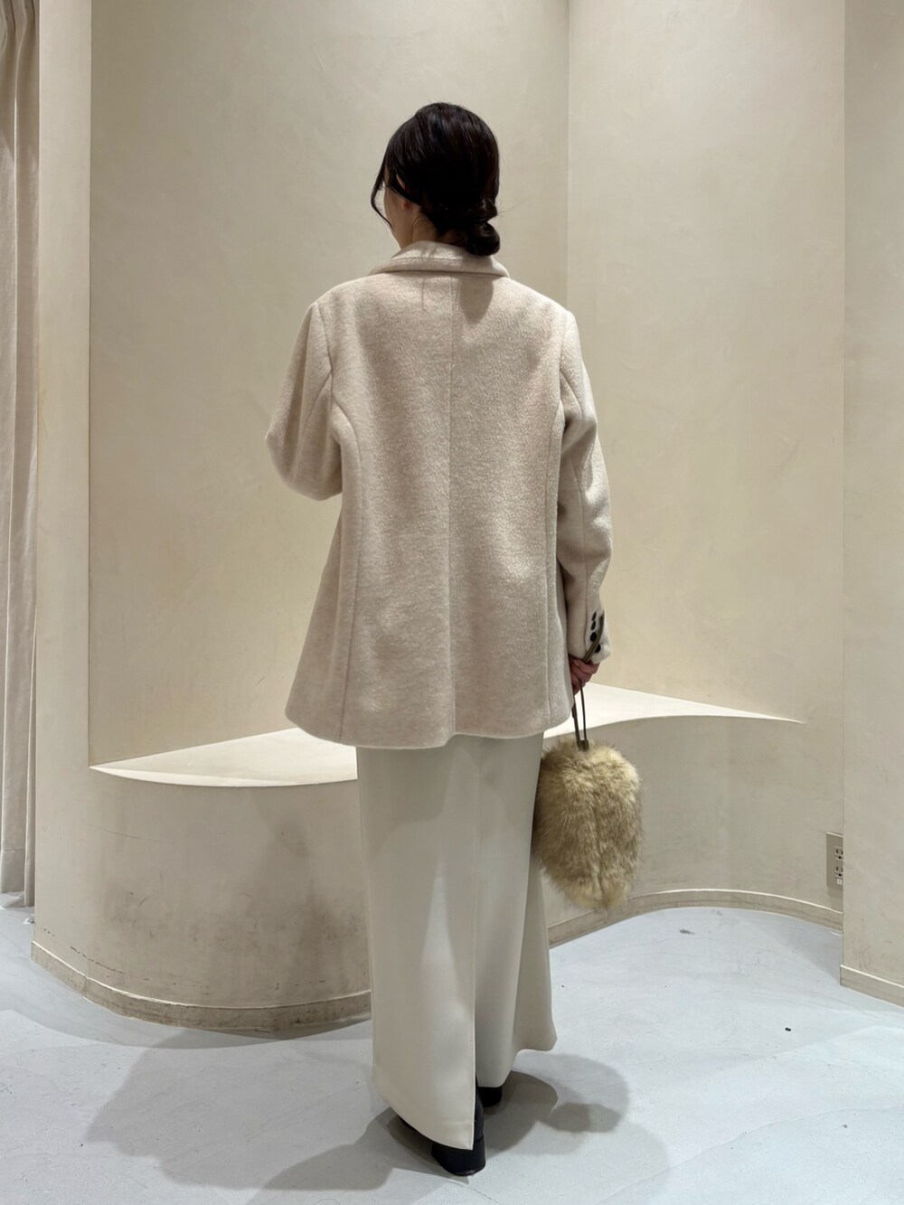 ベージュ系のテーラードジャケット、ブラック系のニット/セーター、イエロー系のショルダーバッグを着用したレディースの冬コーディネートの3枚目の写真