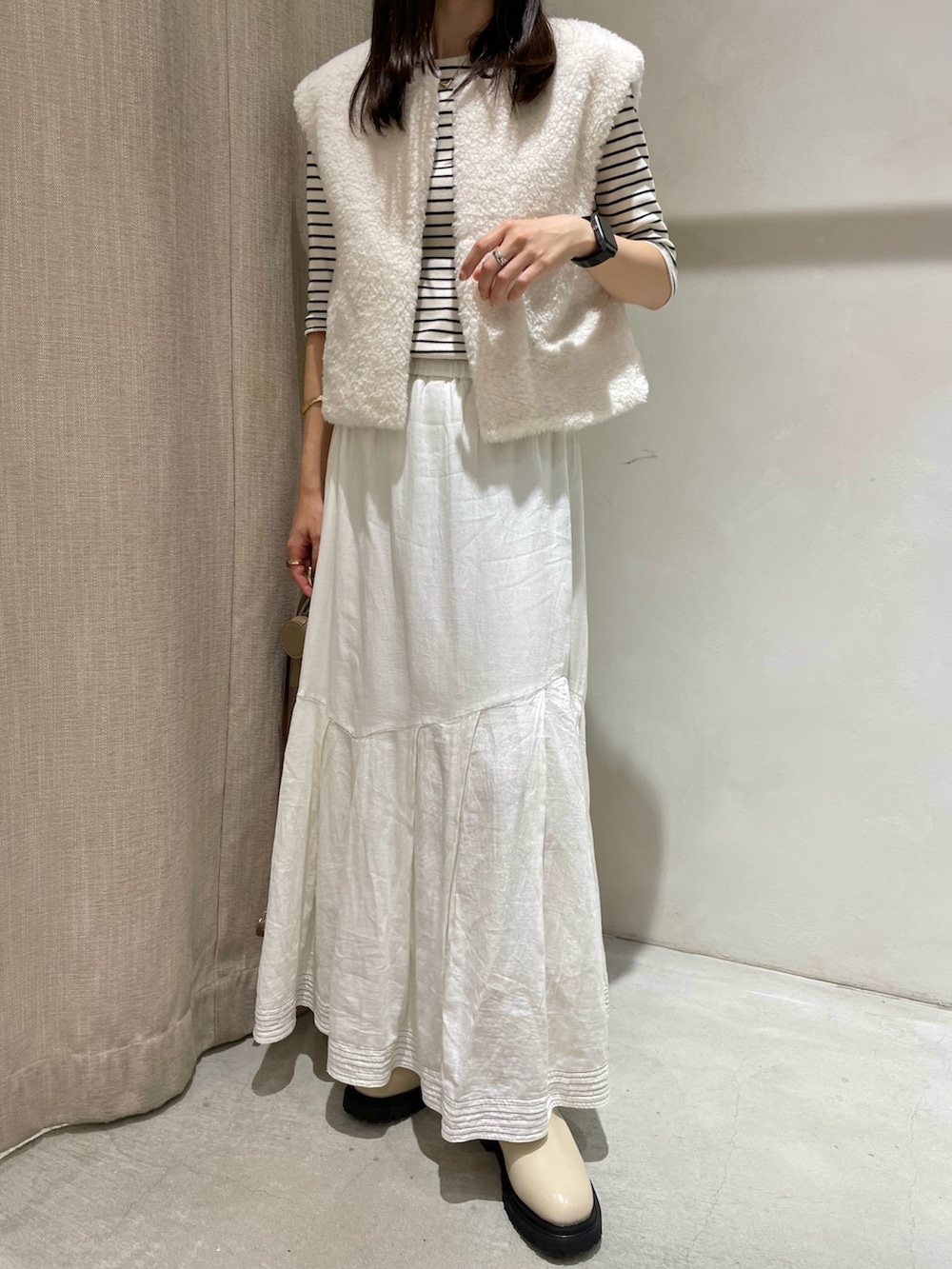 ホワイト系のTシャツ/カットソー、ホワイト系のベスト、ホワイト系のスカートを着用したレディースの秋コーディネートの2枚目の写真