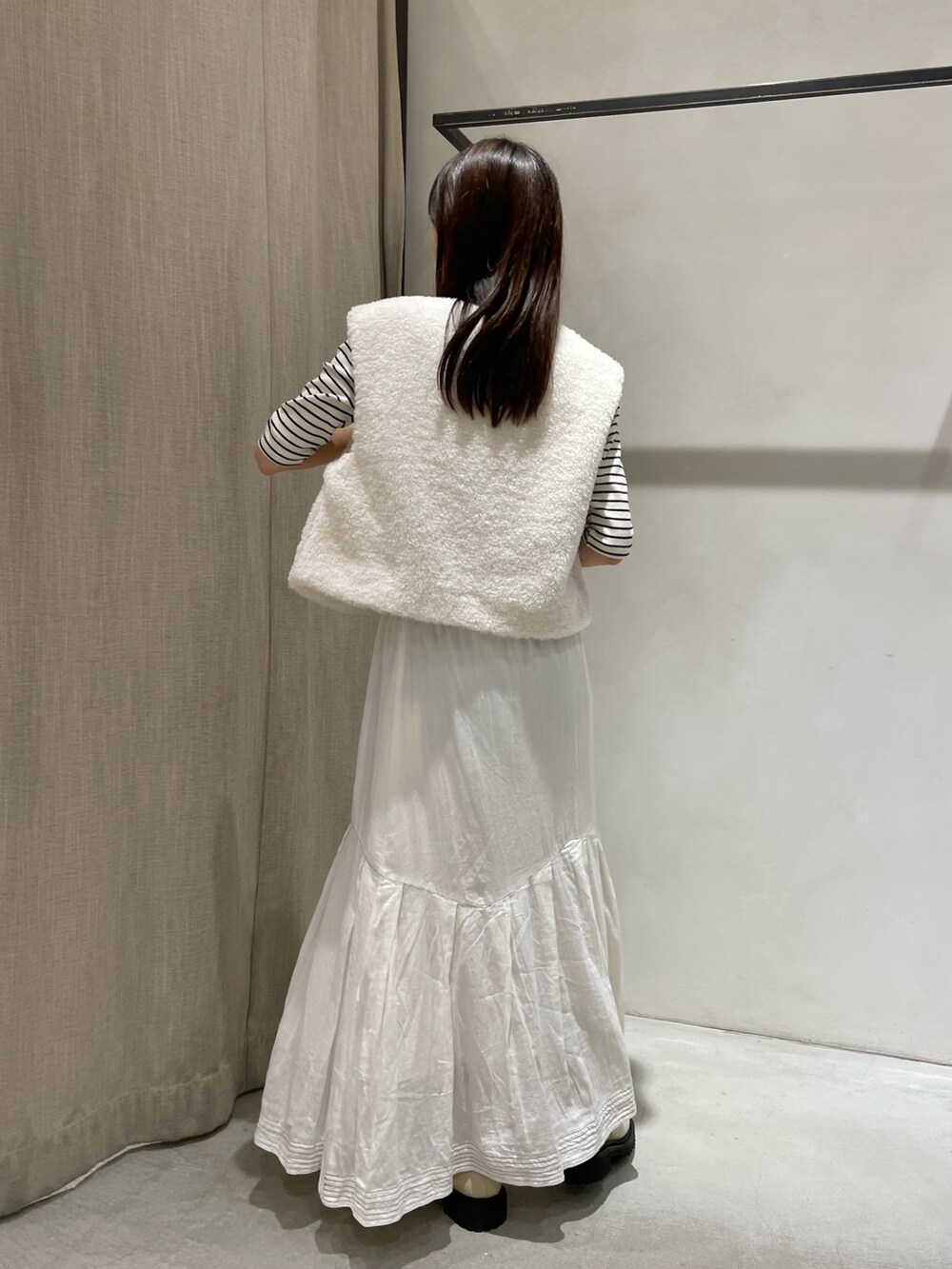 ホワイト系のTシャツ/カットソー、ホワイト系のベスト、ホワイト系のスカートを着用したレディースの秋コーディネートの3枚目の写真