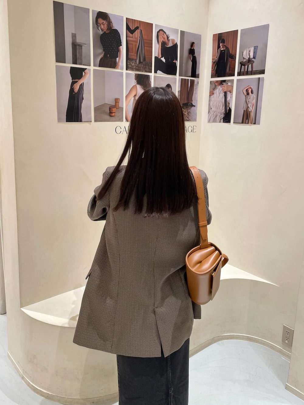 ブラウン系のテーラードジャケット、ブラック系のデニムスカート、ホワイト系のニット/セーターを着用したレディースの秋コーディネートの4枚目の写真