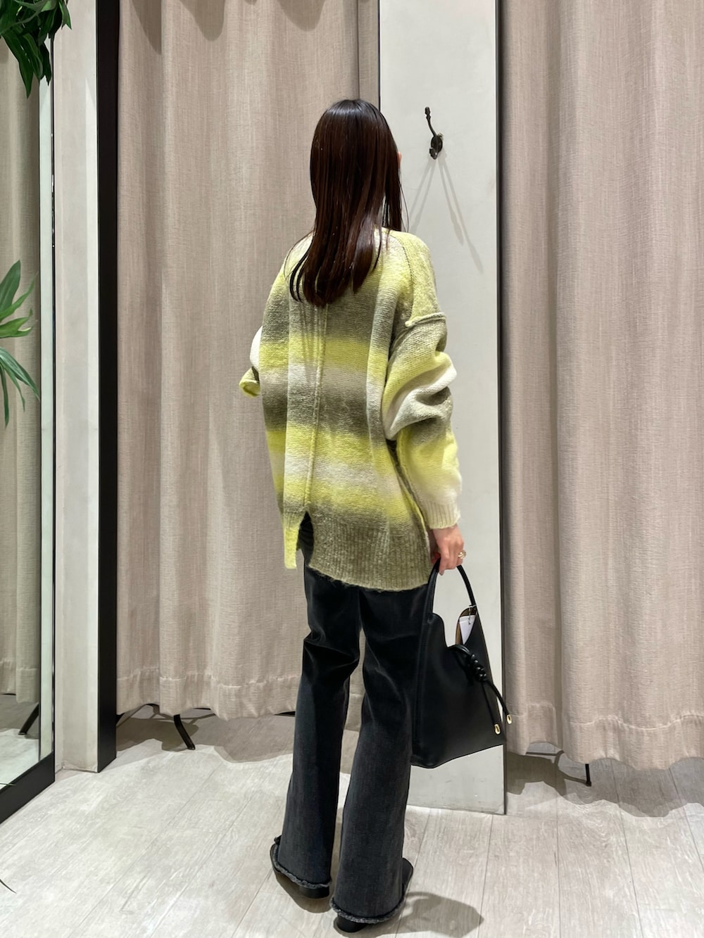 ブラック系のハンドバッグ、イエロー系のニット/セーター、ブラック系のデニムパンツを着用したレディースの秋コーディネートの3枚目の写真