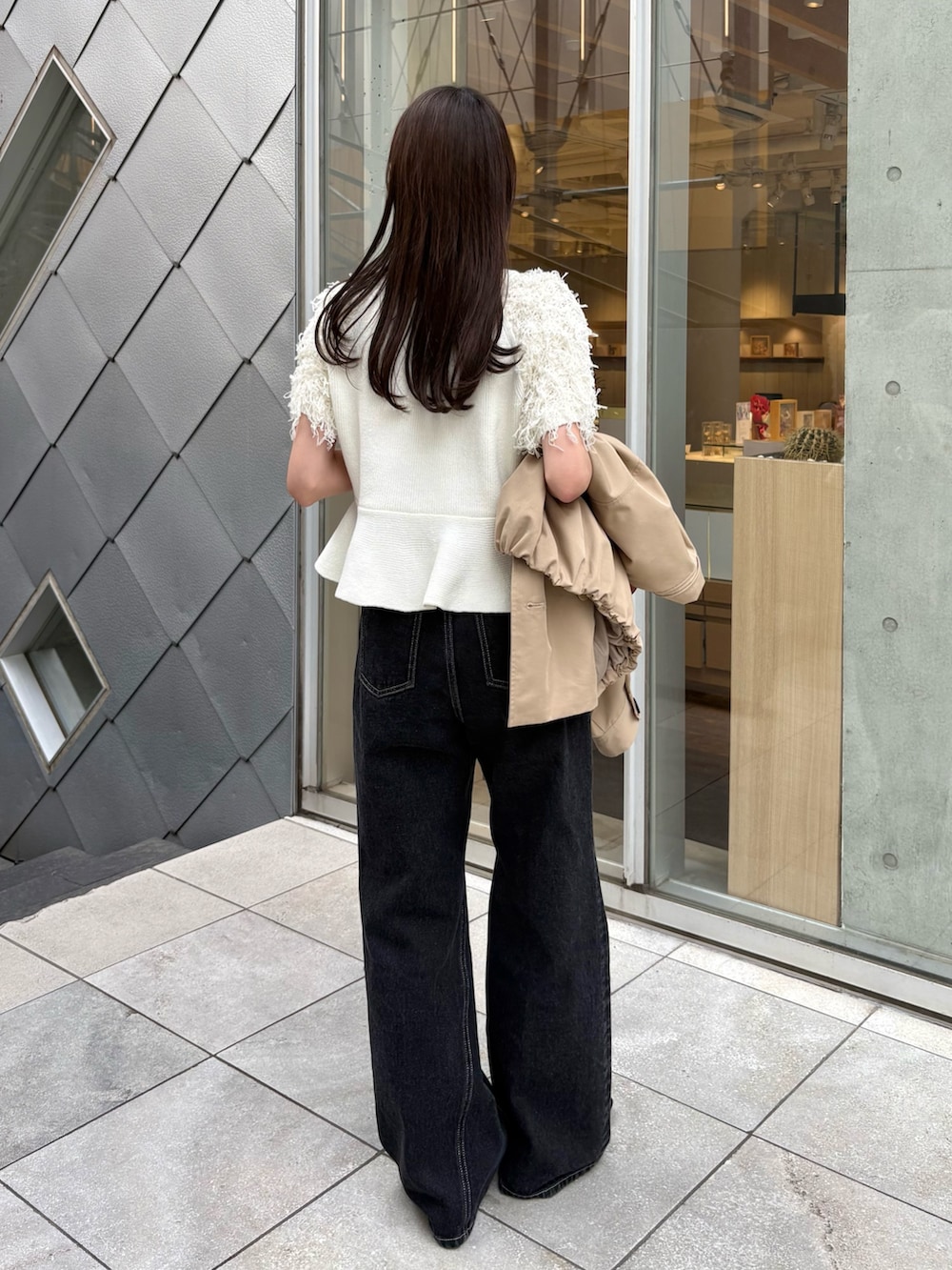 ブラック系のデニムパンツ、ホワイト系のニット/セーター、ベージュ系のトレンチコートを着用したレディースの春コーディネートの5枚目の写真