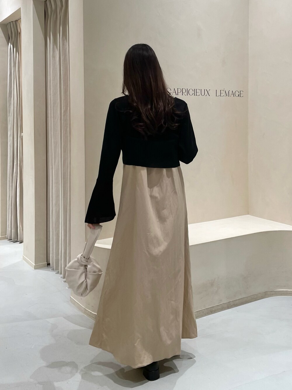 ベージュ系のワンピース、ホワイト系のハンドバッグを着用したレディースの春コーディネートの2枚目の写真