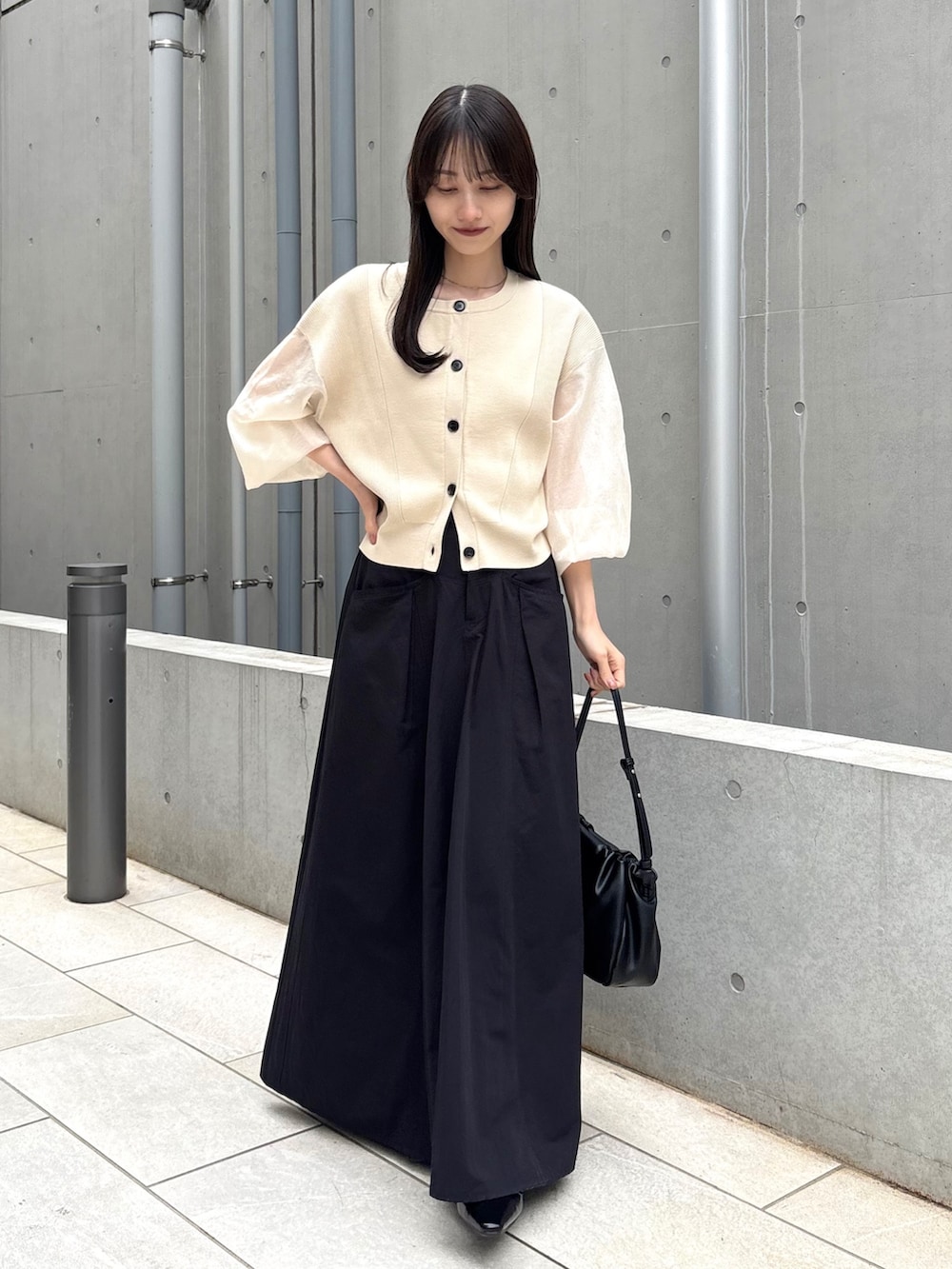 ブラック系のスカート、ベージュ系のカーディガン/ボレロ、ブラック系のパンプスを着用したレディースの春コーディネートの3枚目の写真