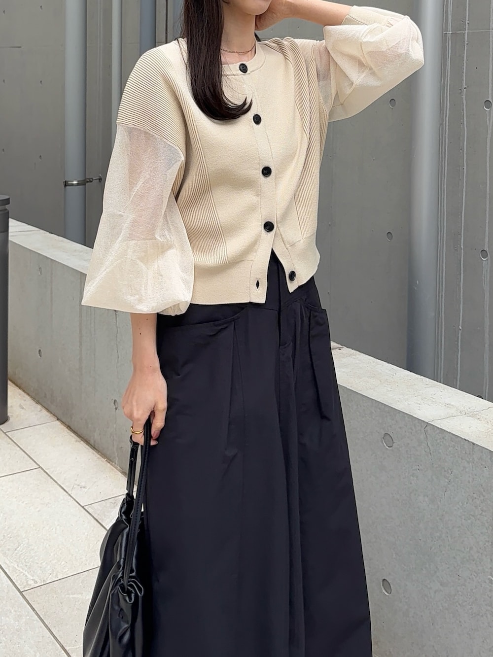 ブラック系のスカート、ベージュ系のカーディガン/ボレロ、ブラック系のパンプスを着用したレディースの春コーディネートの4枚目の写真