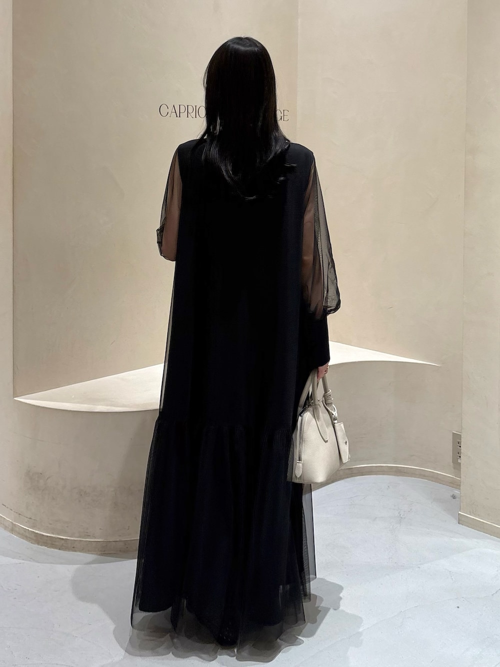 ブラック系のワンピース、ホワイト系のショルダーバッグ、ブラック系のパンプスを着用したレディースの春コーディネートの4枚目の写真