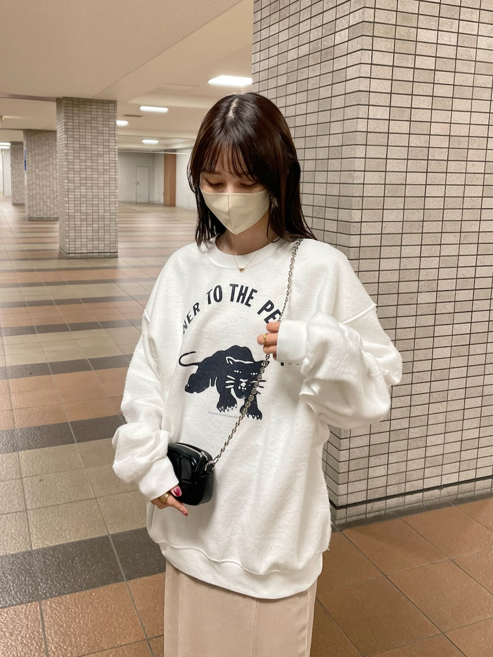 ホワイト系のスウェット、ベージュ系のスカート、ブラック系のトートバッグを着用したレディースの冬コーディネートの2枚目の写真