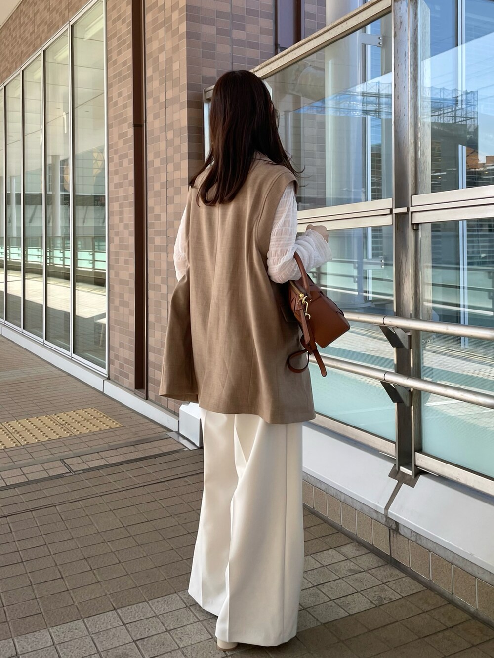 ホワイト系のその他パンツ、ホワイト系のTシャツ/カットソー、ブラウン系のベストを着用したレディースの春コーディネートの3枚目の写真