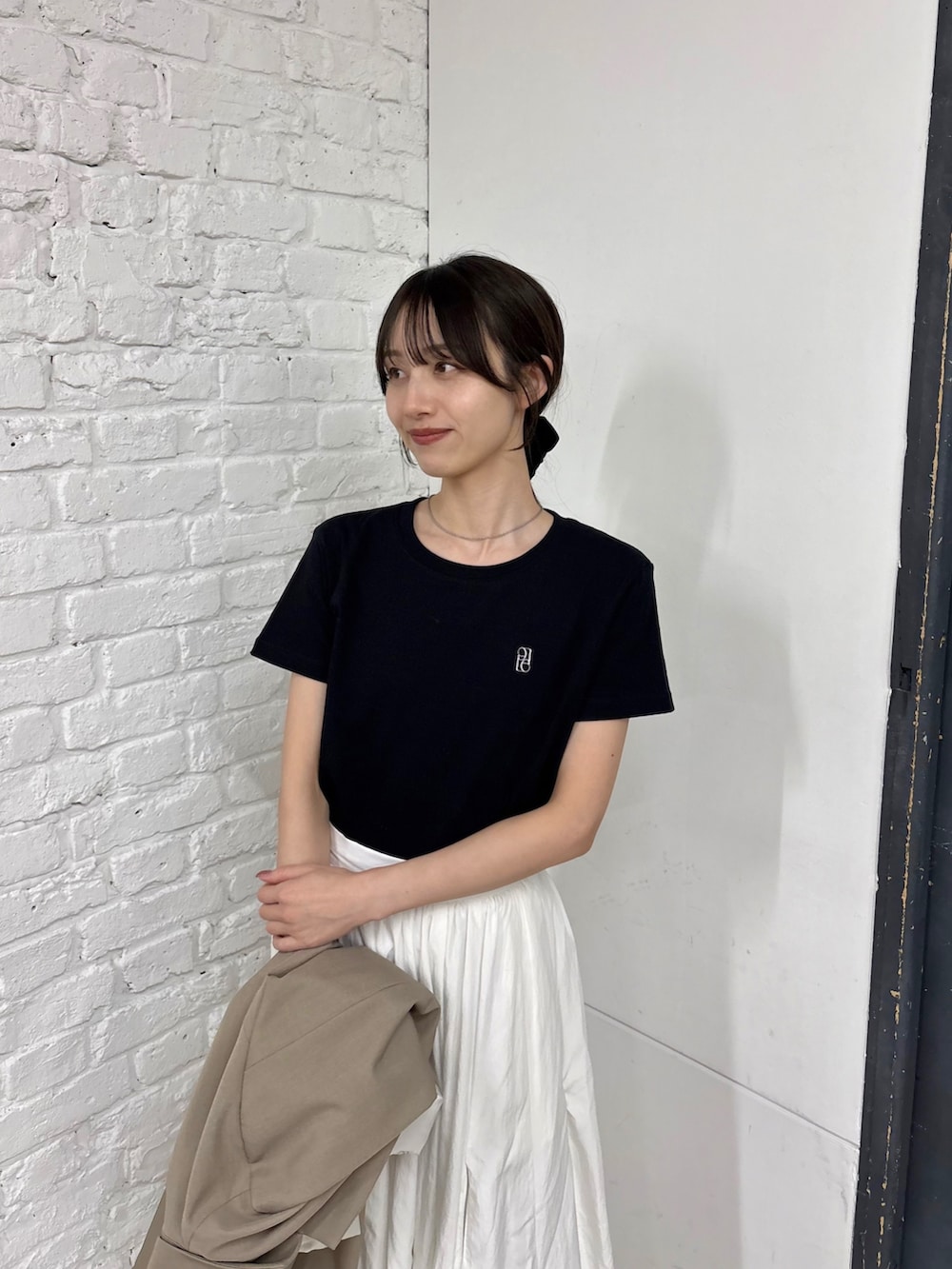 ホワイト系のスカート、ベージュ系のテーラードジャケット、ブラック系のTシャツ/カットソーを着用したレディースの春コーディネートの2枚目の写真