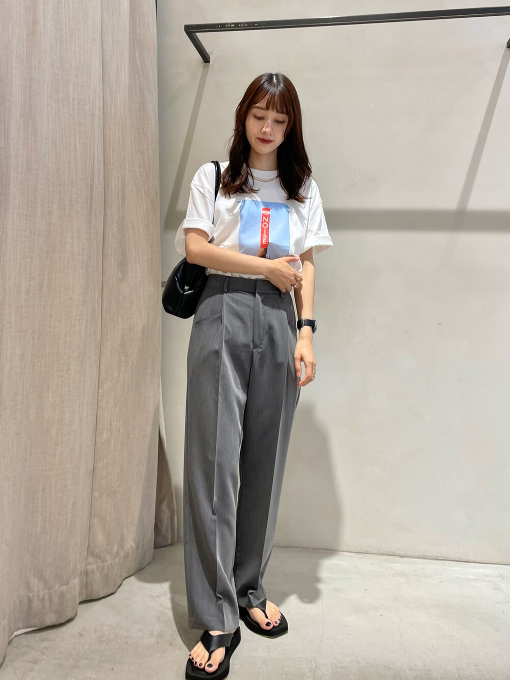 ホワイト系のTシャツ/カットソー、グレー系のスラックス、ブラック系のサンダルを着用したレディースの夏コーディネートの2枚目の写真